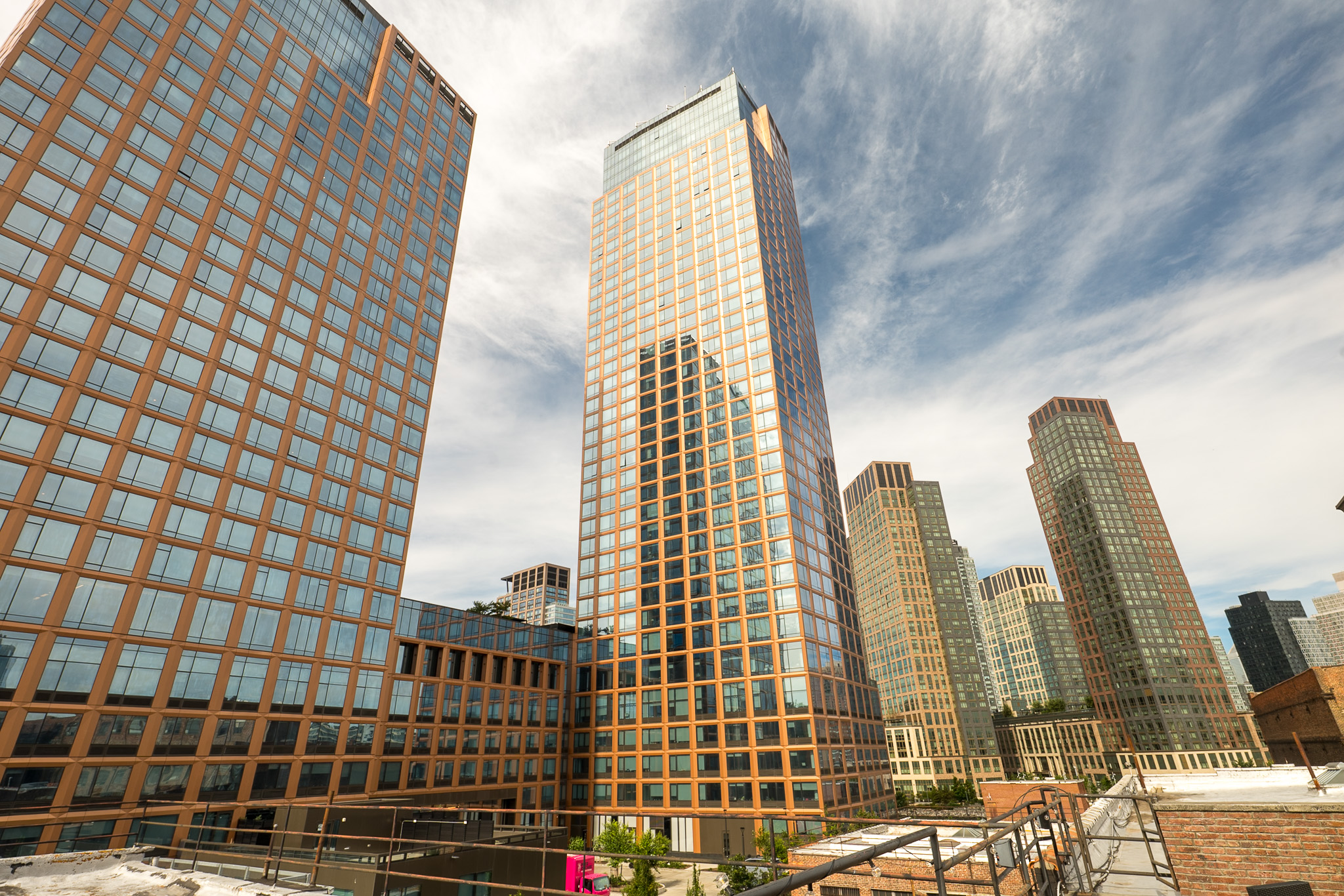Glass and brick city towers seen from a rooftop under a cloudy sky